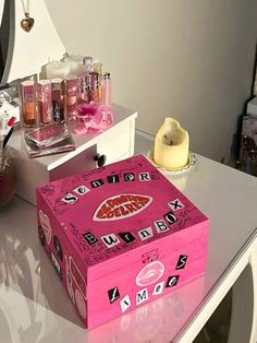 a pink box sitting on top of a white table next to a mirror and vase