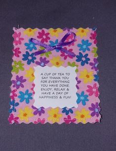 a pink and blue flowered card with a purple ribbon on it that says, a cup of tea to say thank you