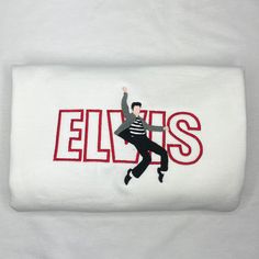 the elviss logo is embroidered on a white shirt with red letters and a man dancing