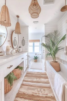 a bathroom with white walls and flooring has plants in baskets on the counter, along with hanging lights