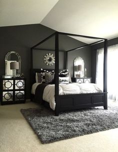 a black and white bedroom with four poster bed, mirrored nightstands, and rug