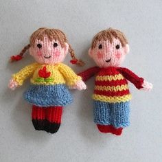 two knitted dolls are hanging on the wall, one is wearing a red and yellow sweater