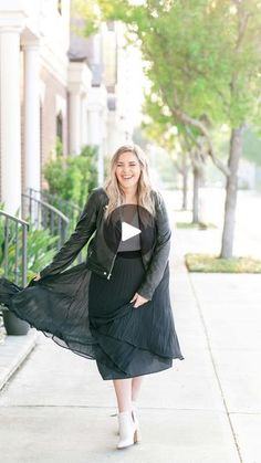 a woman in a black dress is walking down the sidewalk