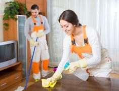 a man and woman cleaning a table in the living room