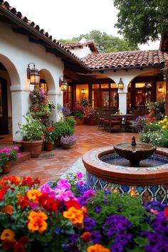 a courtyard with flowers and a fountain in the center surrounded by potted planters