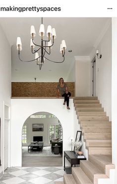 a woman is sitting on the top of stairs in a large room with chandelier