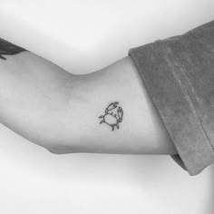 a black and white photo of a crab tattoo on the left inner arm, which has a small fish in it's center