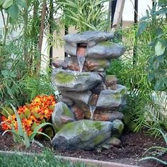 there is a fountain made out of rocks in the garden