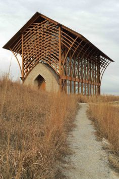 a wooden structure sitting on top of a dry grass covered field next to a dirt road