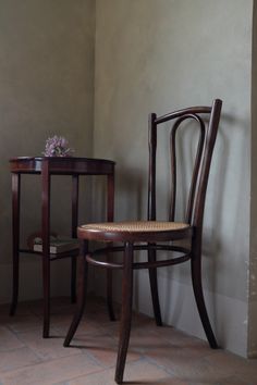 a wooden chair sitting next to a table with a vase on it's side