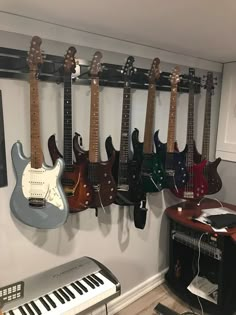 several guitars are hanging on the wall next to an electronic keyboard and musical instrument rack