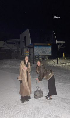 two women standing in the snow, one holding a basket