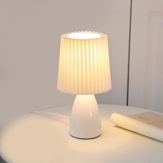 a white lamp sitting on top of a table next to a book