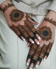 a woman's hands with henna tattoos on them