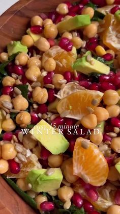 a salad with avocado, oranges and other fruits in it on a wooden platter