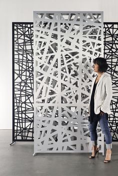 a woman standing in front of a sculpture made out of black and white lines on the wall