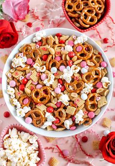 valentine's day snack mix in a white bowl on a pink table with red roses