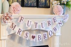 a fireplace mantel decorated with pink flowers and fabric banner that says future mrs brown