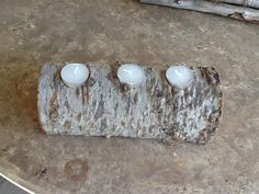 three candles sitting on top of a piece of wood with two white ones in the middle