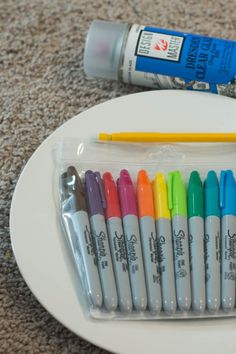 several markers are sitting on a plate next to a bottle of water and a marker pen