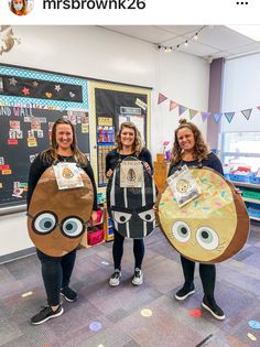 three girls are holding up their costumes in the classroom