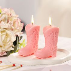 two pink candles sitting on top of a white plate next to flowers and a bouquet