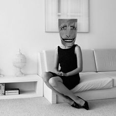 a woman sitting on top of a couch wearing a paper bag over her head with eyes