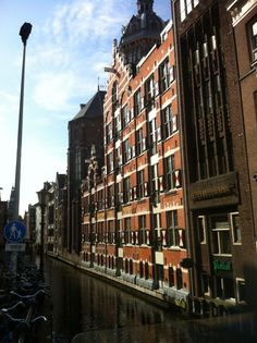 an old brick building next to a canal with bicycles parked on the side by it