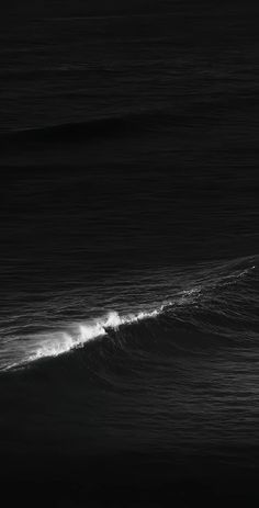 a man riding a wave on top of a surfboard in the ocean at night