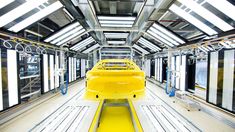 a yellow car is parked in a large building with lots of windows on the ceiling