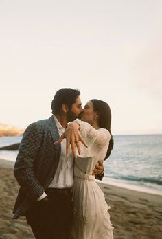 a man and woman kissing on the beach