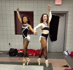 two young women in black and white outfits dancing on the floor with their hands up