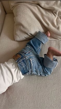 a little boy laying on top of a couch