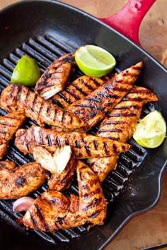 grilled chicken and limes on a grill with a red spatula next to it