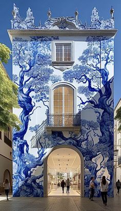 people walking in front of a blue and white building with trees painted on the side