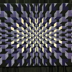 a large purple and black quilt on display