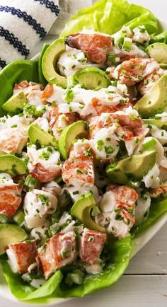 a white plate topped with lettuce and cucumber salad next to a striped dish towel