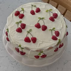 a cake with white frosting and raspberries on it sitting on a table