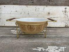 a gold and white bowl sitting on top of a wooden table