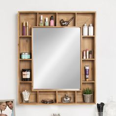 a bathroom vanity with a mirror above it and shelves on the wall holding personal items