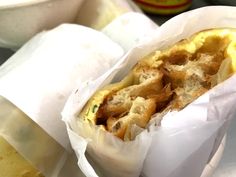 an omelet wrapped in wax paper on top of a table next to a bowl