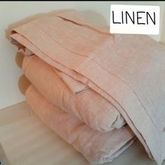 three folded linens sitting on top of each other next to a white wall with the word linen written across it