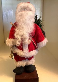 a santa clause figurine with bell on wooden stand