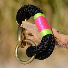 a close up of a chain on a piece of wood with a pink and green bracelet