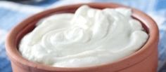 a brown bowl filled with cream sitting on top of a blue and white checkered table cloth