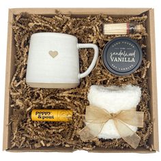 a gift box containing an empty coffee mug, cinnamon sticks, and other items