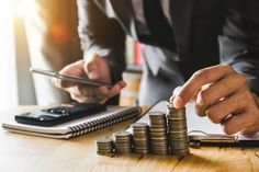 business man stacking coins with calculator and laptop on wooden table in office