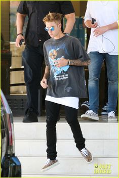 the young man is walking down the steps with his hand in his pocket and wearing sunglasses