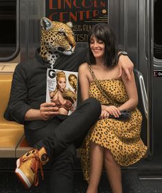 a man and woman sitting next to each other in front of a bus with a leopard mask on