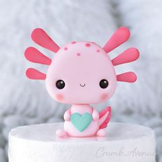 a pink and blue toy sitting on top of a white cake